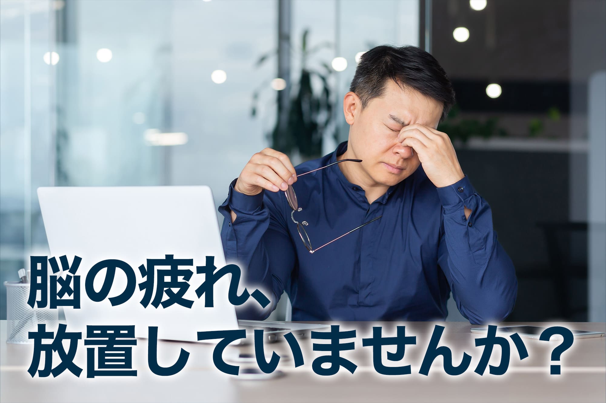 目を押さえて疲労を感じるビジネスマン