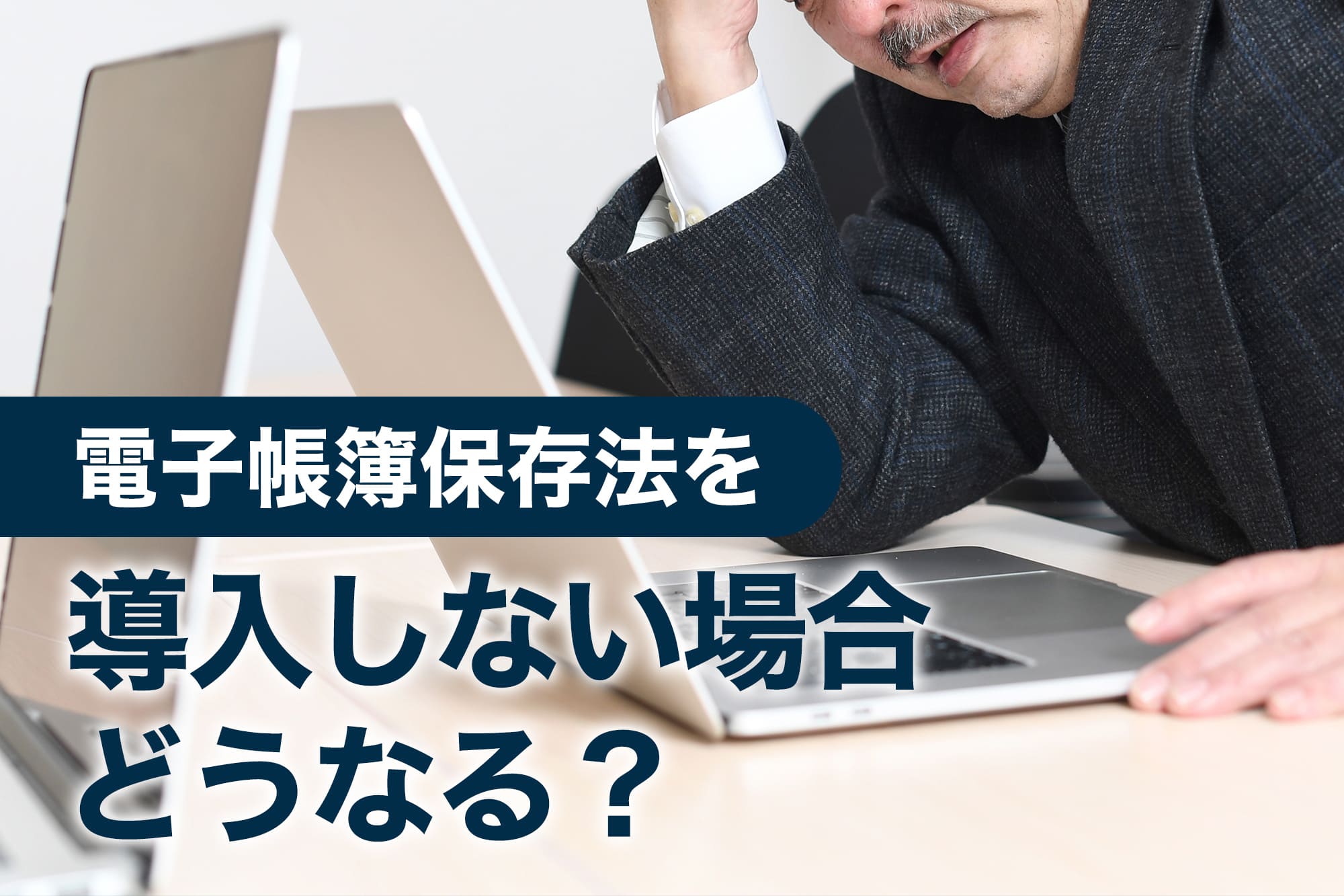 額に手を当てて悩む中年男性とノートパソコン